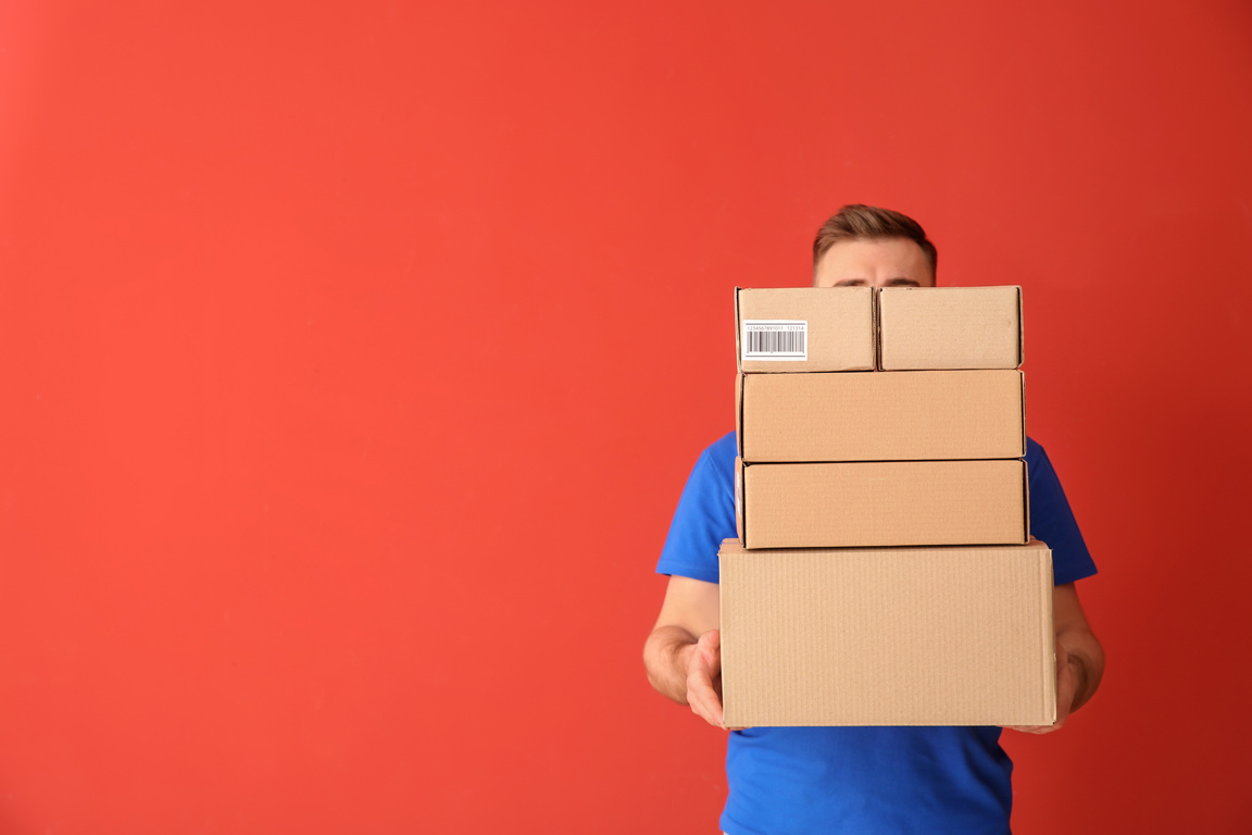 Delivery Man with Boxes on Color Background